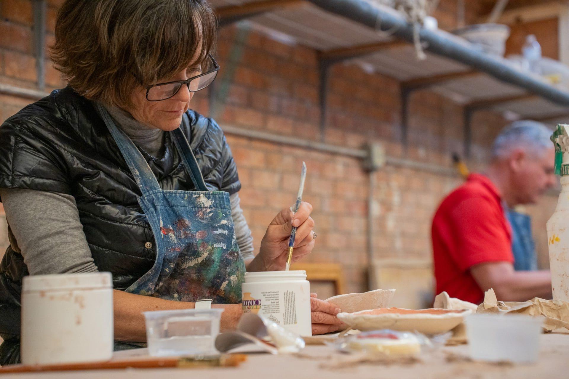 Woman painting in ceramics workshop.